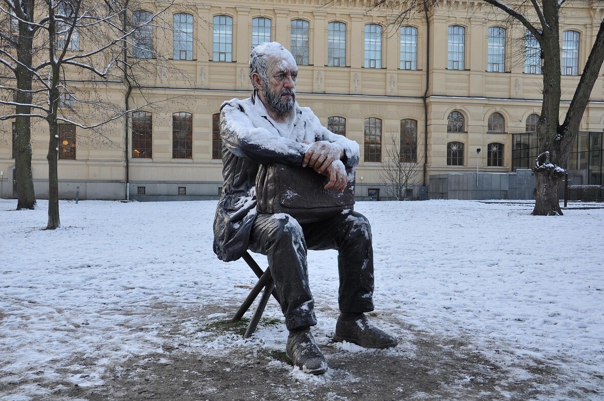 Statue of a man sitting outdoors covered in snow during winter
