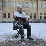 Statue of a man sitting outdoors covered in snow during winter