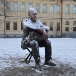 Statue of a man sitting outdoors covered in snow during winter