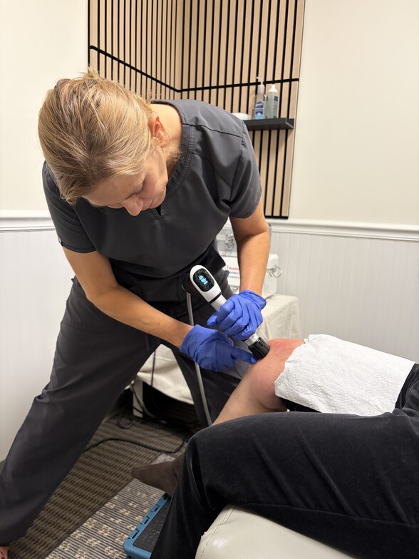 Chiropractor Applying Shockwave to the Knee of a Patient